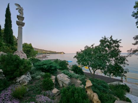 Monument with white, antique column on the green seashore. As if the photo from the era of Hercules, Prometheus and other heroes
