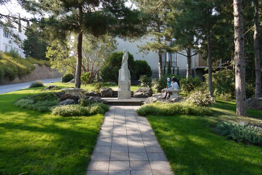 Holidaymakers are sitting on a bench in front of a beautiful decorative sculpture