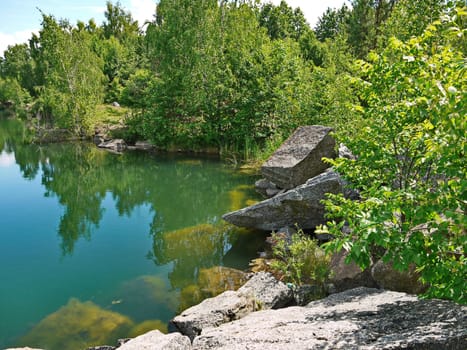 Rocky coast with large stone boulders at the transparent deep blue river