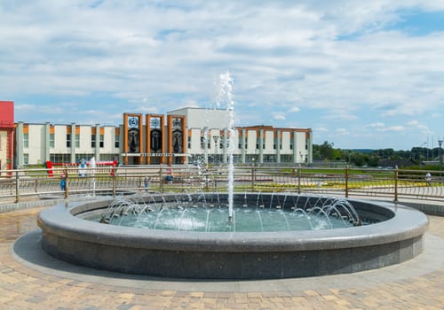 modest round fountain on the square near the building of the city center of culture