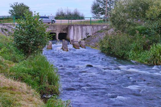 car bridge over a small, stormy river with foggy water on rapids