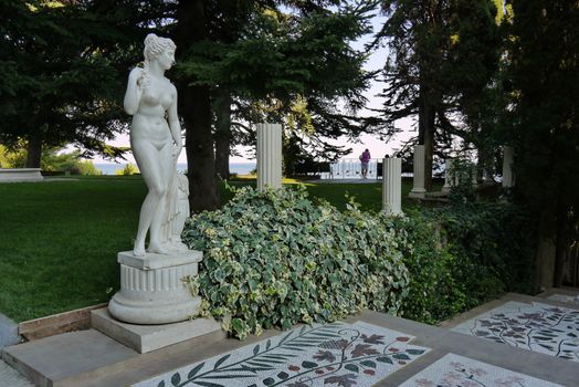 a magnificent plaster statue of a woman in a recreation park and a sea far away