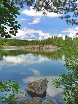 a deep blue sky with slowly floating clouds and a sleepy little pond at the bottom