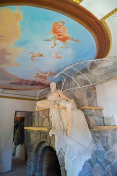 a statue of a naked woman on a stone fireplace under the painted ceiling in the room