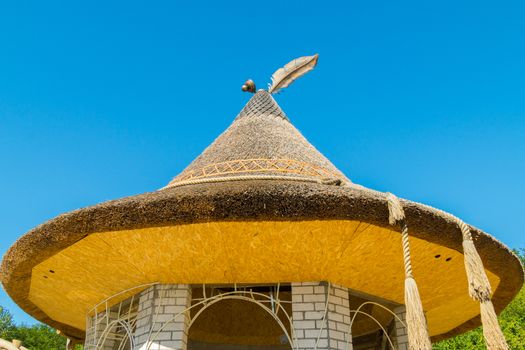 extraordinary design of a gazebo with a reed roof and elements of forging in the form of a charming bonnet