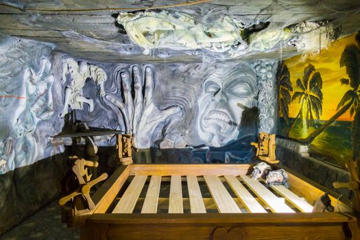 The wall of the room with unusual frightening sculptures and wooden mechanisms