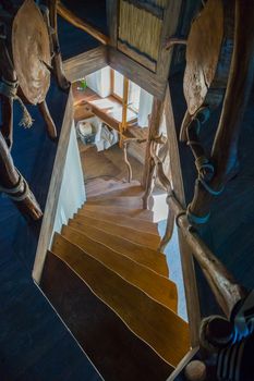 A steep wooden staircase on the lower floor to the window in the house with an interesting interior