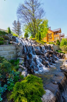beautiful waterfall on the background of beautiful plants and a country house