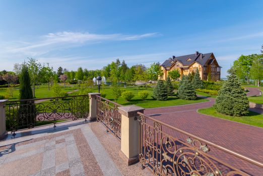 A viewing platform with beautiful, wrought-iron handrails near the park with green trees and stone alleys