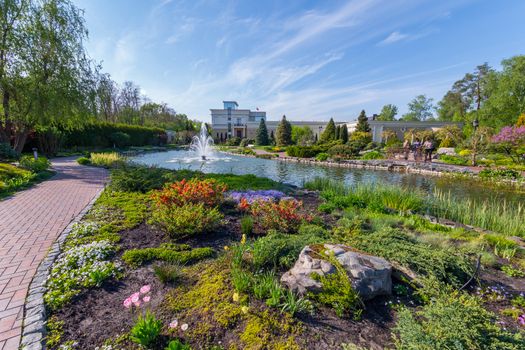 Landscape design in a park with a fountain on the lake near the house