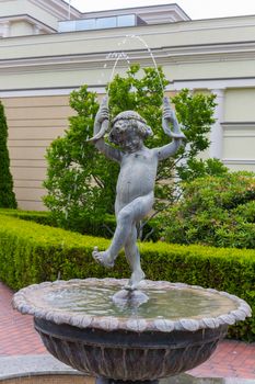 beautiful fountain in the recreation area in the form of a sculpture of a boy standing in a bowl with water