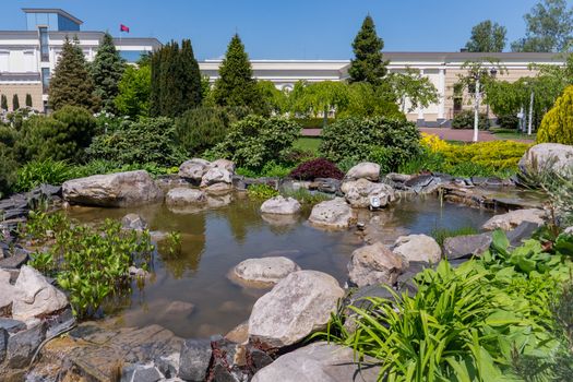 a rocky bottom of an artificial lake with a cascading fountain on a botanical sunny day