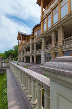 Fence with handrails near the beautiful house with a lot of balconies with columns supporting the stucco.