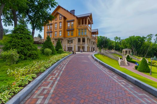 The alley is decorated by hosts leading to a beautiful large wooden house with balconies. Novi Petrivtsi, Ukraine