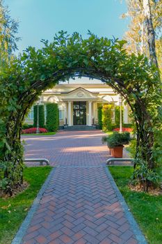 A wooden arch from branches on deer from the tiles leading to the entrance to the yellow building