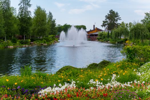 a magnificent variety of flowers growing on the shore of a pond with fountains