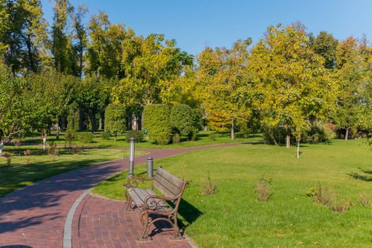 a comfortable bench in the park with a green lawn behind it