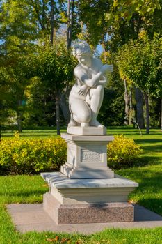 beautiful plaster sculpture of a sitting woman in a park on a carpet of green grass