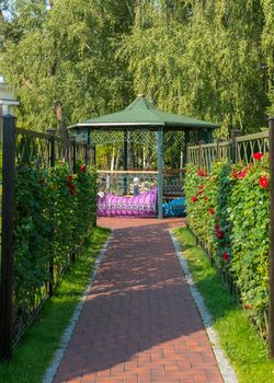 Alley leading to a beautiful decorative gazebo with a green roof and a fence