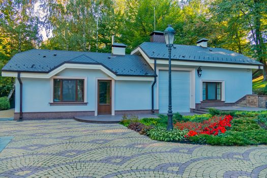 a clean, spacious yard with a flower bed in front of the house on the background of the hill