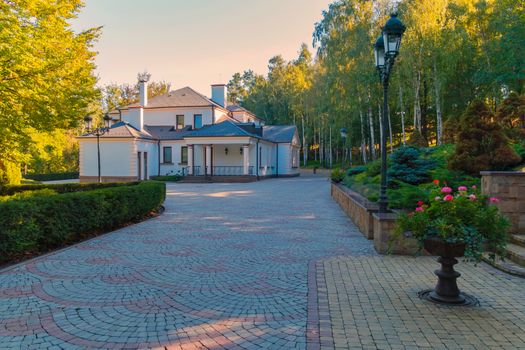 Beautiful flower beds and green decorative bushes along the alley leading to the modern building