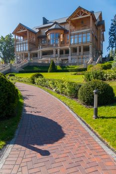 Magnificent house against a blue sky with glass verandas standing in a park with green lawns and paths.