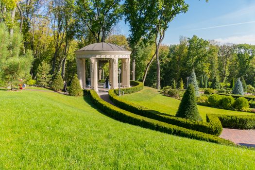 Arbor with beautiful, chopped creslons in a green, spring park. Ideal place for a wedding photo session. What a guy and a girl used