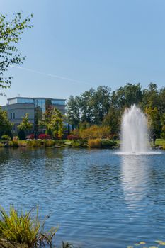 A tall fountain sprays foam water over a lake in a park against a blue sky background. Mezhygirya Ukraine