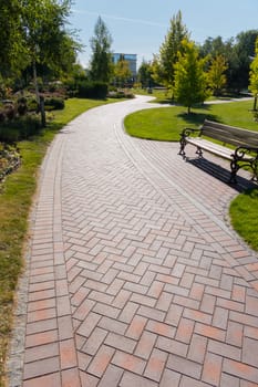 a clear path in the park, brightly lit by the sun, with a beautiful lounge bench