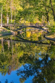 Figured bridge with patterns over a pond reflecting the sky and trees