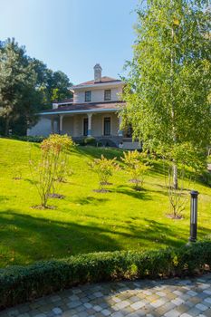 Saplings of trees and bushes on the green lawn in the park on the background of the house