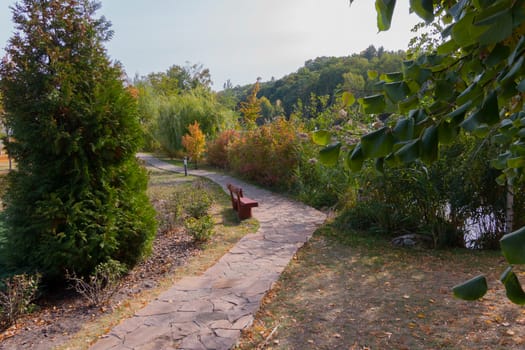 A walking promenade stretching along the park with large bushes and benches
