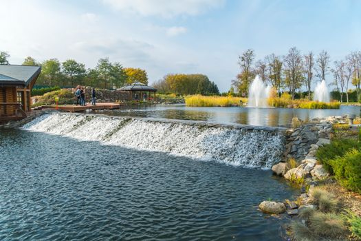 a small artificial dam in the park on the background of fountains and tourists photographing this beauty