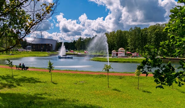 shore of the lake with young trees on the background of a lake with fountains