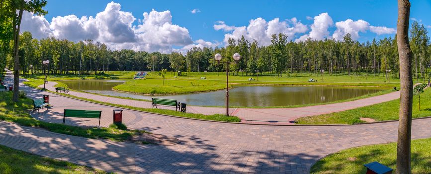 A small decorative lake with an island on it against the backdrop of a green park zone