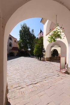 A huge arch leading to the entrance to a spacious area lined with stone