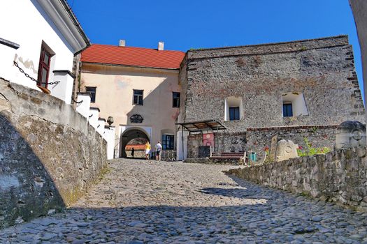 road paved with gray cobblestone and tourists going far away