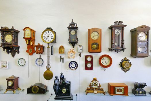 A collection of antique watches of various shapes and sizes placed on a white wall in the museum's premises.