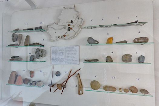 Museum exposition with numbered tools of ancient world work behind glass