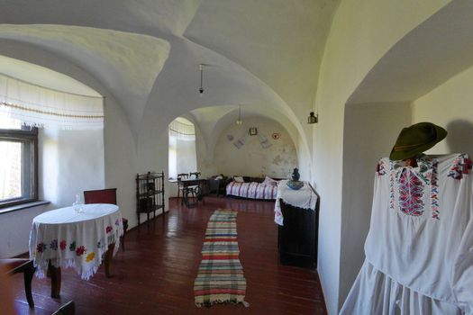 Installation of a village house with whitewashing on the walls, embroidered with a towel and tablecloths, wooden floor. Lamps on the ceiling out of place