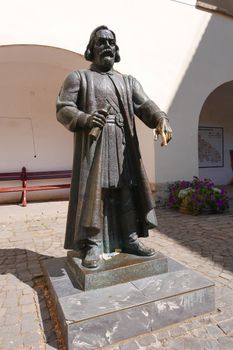 Bronze monument on the background of the arches of the ancient castle