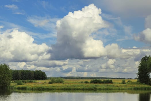 field on the river bank under beautiful clouds