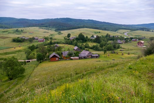 Small rural houses with courtyards on the background of wide green mountain ranges