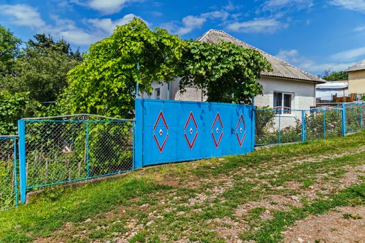 Private sector with a blue gate in a red pattern. A vineyard grows above the gate