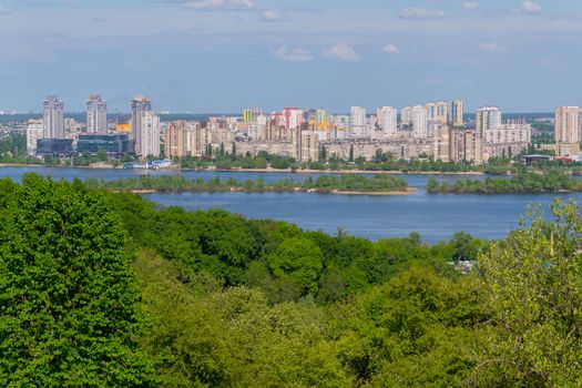 Panorama of multi-storey buildings on the shore of the Dnipro River under the blue sky. Kiev. Ukraine