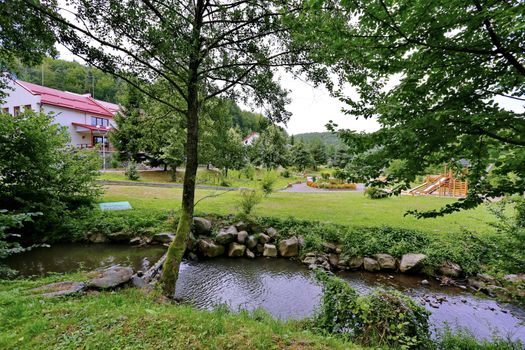 transition from the stones through a shallow stream leading to the playground and flowers growing next to it