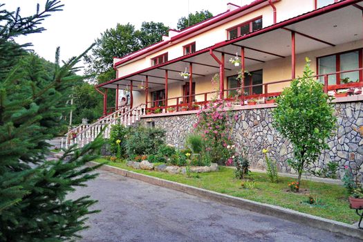 Two-story building with a red gutter and a fence, decorated with flowers
