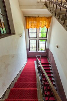 The red track is laid down the stairs down to the window with orange curtains