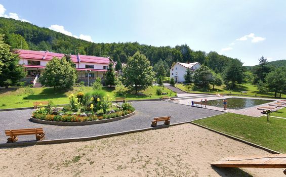 A flower bed with yellow flowers and stones on the pool area in the hotel complex in the mountains