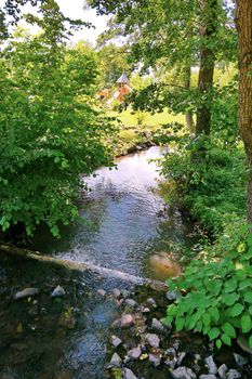 Transparent mountain stream, breaking stone boulders on its way against the background of green deciduous trees